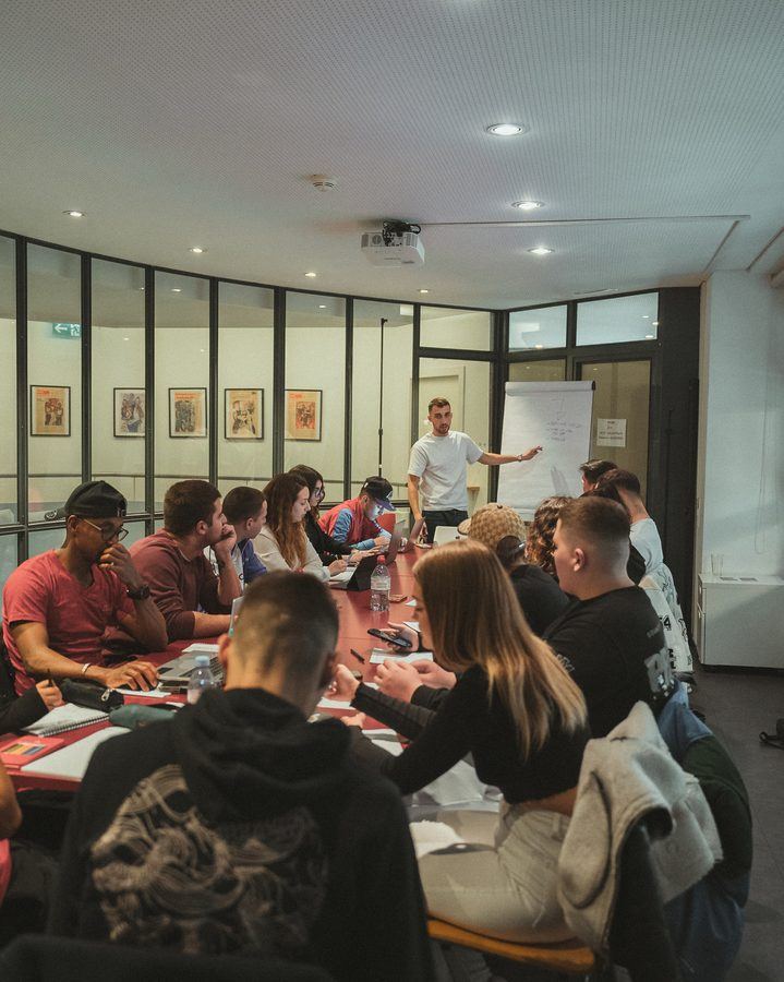 Un relatore in piedi davanti a un tavolo di persone che seguono una formazione in una sala riunioni