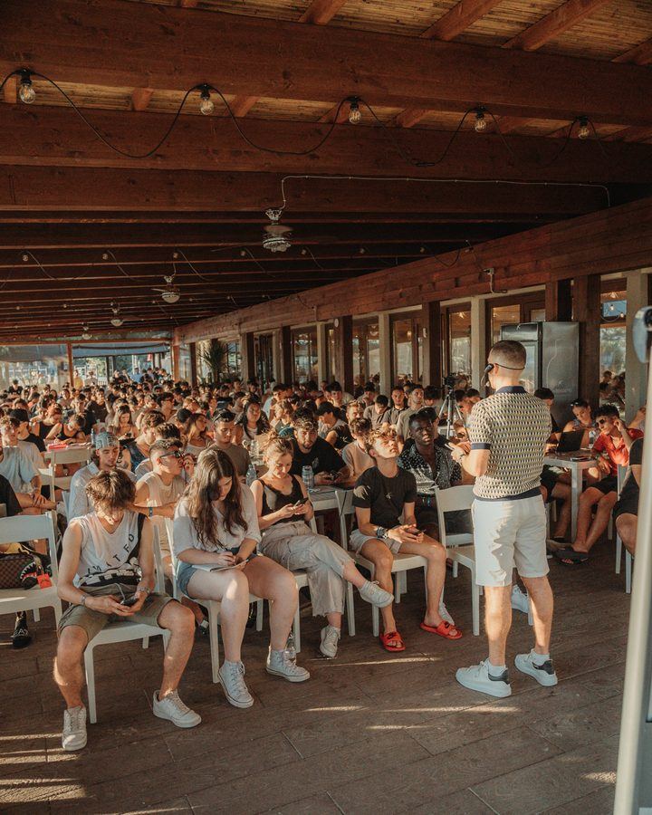 Una sala con tettoia in legno piena di persone sedute durante un evento della community